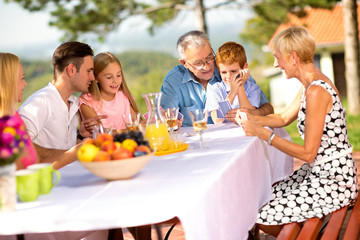 Happy family sitting at table outdoor.