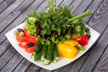  juicy, summer vegetable salad cutting from fresh vegetables and greens in a beautiful serving on a wooden table for decoration and design