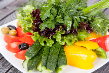  juicy, summer vegetable salad cutting from fresh vegetables and greens in a beautiful serving on a wooden table for decoration and design