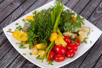  juicy, summer vegetable salad cutting from fresh vegetables and greens in a beautiful serving on a wooden table for decoration and design