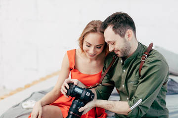 Naklejka na ściany i meble young couple checking good photos while sitting on the sofa, close up photo. happy man and woman selecting best photos after photo session, successful shot