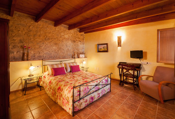 Nice warm interior of bedroom in a rustic style in country house or hotel. Wooden beams and walls...