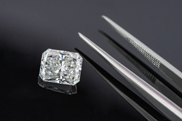 Radiant cut diamond with tweezers on black background