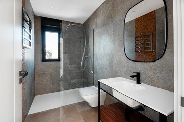 Modern bathroom with a glass bathtub and luxury washbasin. The walls and floor are covered with modern tiles.