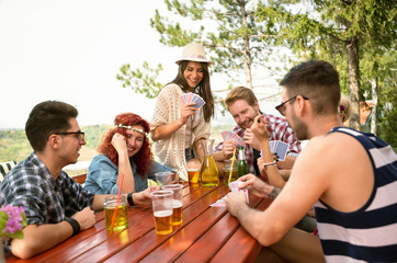 Young friends in nature play cards with lot drinks at table