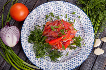  juicy, summer vegetable salad cutting from fresh vegetables and greens in a beautiful serving on a wooden table for decoration and design
