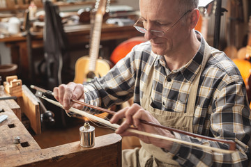 Instrumentenbauer beim Erhitzen von Bogenhaar