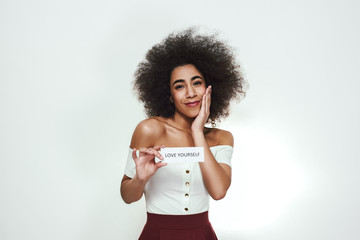 Open your heart... Positive and happy afro american woman with curly hair holding a sheet of paper...