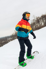 young man standing on his board at a winter resort, full length photo. healthy lifestyle, health care