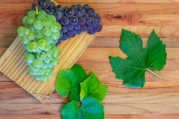 Wine background, bunch red and white grapes, cork, corkscrew, wine leaves, grapes on vintage background, wine concept. Top view on a wooden board.