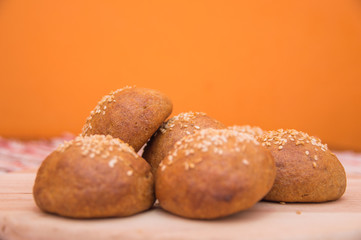 Tasty buns with sesame, on wooden background