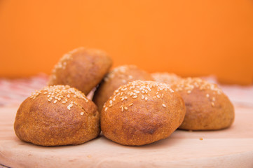 Tasty buns with sesame, on wooden background