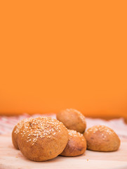 Tasty buns with sesame, on wooden background