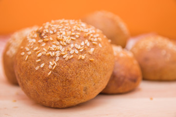 Tasty buns with sesame, on wooden background