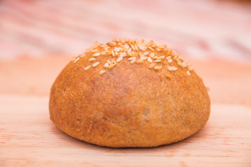 Tasty buns with sesame, on wooden background