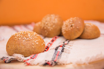 Tasty buns with sesame, on wooden background