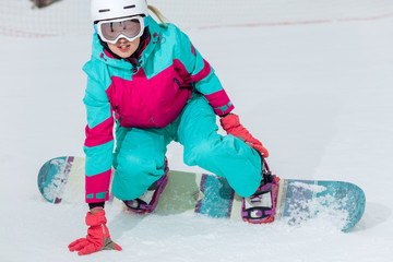 beautiful snowboarder is sitting on the snow, close up photo.awesome girl learning snowboarding