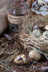 Cute still life with quail eggs. Quail eggs in the nest and on the old wooden table in the barn among vintage items and dried flowers