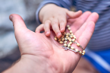 A child takes a rosary from his dad's hand