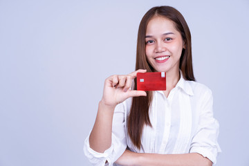 Happy young Asian woman dressed in Business Shirt holding or showing credit card or identification card on gray background. Start up or investment ,small business or Identity verification concept
