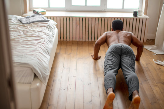 Hardwworking Man Performs Pushup On Floor In The Bedroom With Modern Interior. Close Up Back View Photo, Hobby, Interest