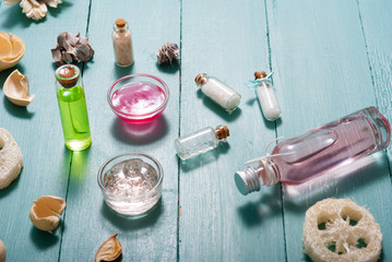 shampoo, shower gel, perfume and bath salt samples on wet old blue wood table background