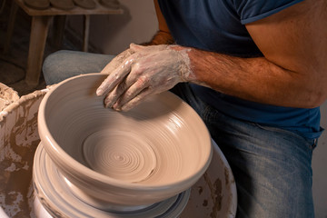 Professional potter making bowl in pottery workshop, studio.