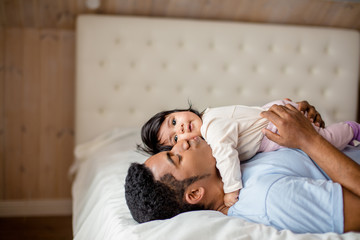 emotional handsome man kissing his daughter while lying in the bedroom, close up side eview photo, tender feeling