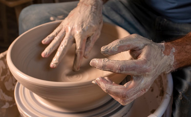 Professional potter making bowl in pottery workshop, studio.