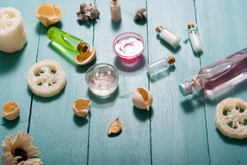 shampoo, shower gel, perfume and bath salt samples on wet old blue wood table background
