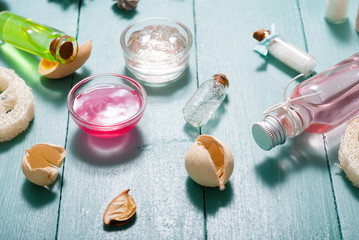shampoo, shower gel, perfume and bath salt samples on wet old blue wood table background