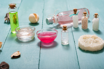 shampoo, shower gel, perfume and bath salt samples on wet old blue wood table background