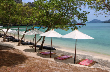 White umbrella with bean bags and mat on the beach at tropical island