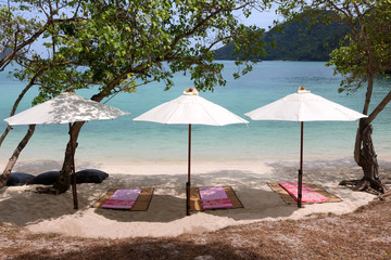 White umbrella with bean bags and mat on the beach at tropical island