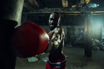 Hands of boxer over dark gym background. Strength, attack and motion concept. Fit african american...