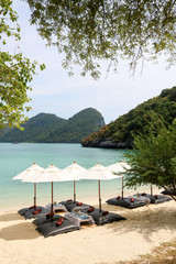 Bean bags with the white umbrella on the beach, set up for lunch at tropical island