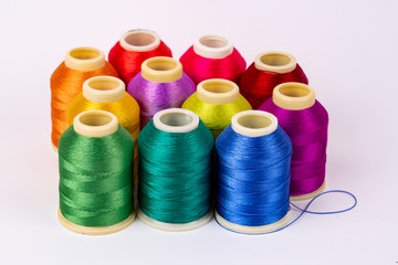 Colored thread coils on white background, sewing, place for text