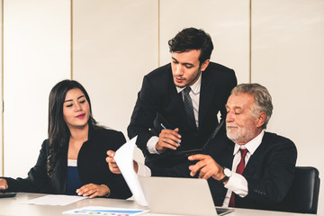 Senior caucasian manager working in office with assistance of young Asian business people and...