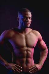 Fototapeta na wymiar Muscular man African bodybuilder. Man posing on a black background, shows his health and perfect shape.