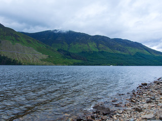 Am Ufer eines Sees im schottischen Highland bei bewölktem Himmel