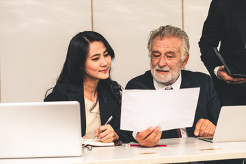 Senior caucasian manager working in office with assistance of young Asian business people and...