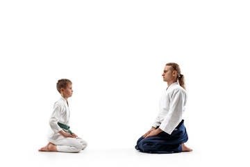Man and teen boy at Aikido training in martial arts school. Healthy lifestyle and sports concept. Fightrers in white kimono on white background. Karate men with concentrated faces in uniform greetings