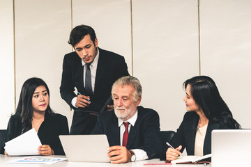 Senior caucasian manager working in office with assistance of young Asian business people and...