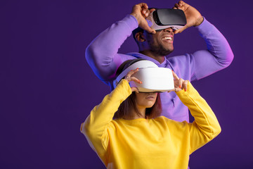 Technology and innovation concept. Two multicultural cheerful people, dressed in yellow and violet...
