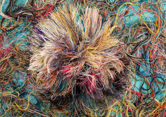 Colorful tangled threads on blue background. Closeup.