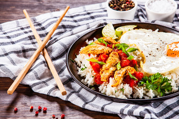 Grilled chicken meat with rice and fried egg on wooden table