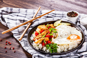 Grilled chicken meat with rice and fried egg on wooden table