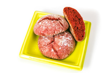 Red cookies with icing sugar on a green plate isolated on white background