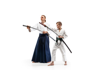 Man and teen boy fighting at Aikido training in martial arts school. Healthy lifestyle and sports concept. Fightrers in white kimono on white background. Karate men with concentrated faces in uniform.