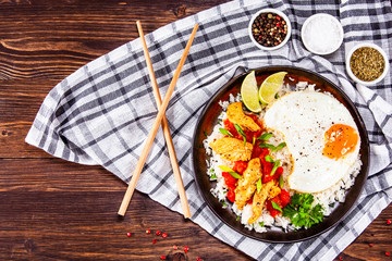Grilled chicken meat with rice and fried egg on wooden table